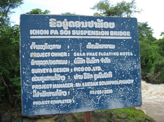 お、吊り橋が見えた。<br /><br />その手前に看板が。<br /><br />この橋を作ったのは誰それと書いてあるのだろう。<br />