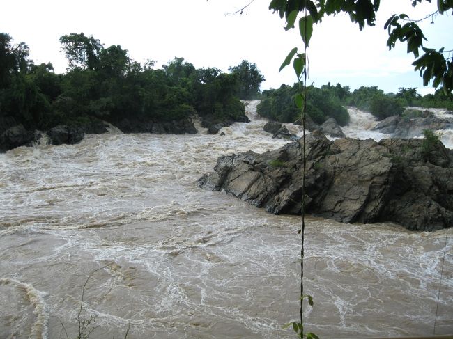 ドードーともの凄い音を立てながら、ものすごい量のて水が落ちる。<br /><br /><br />そういえば、ここで一つ事件があった。<br /><br />滝を見に行く途中のお店でコカ・コーラを買おうとした時だった。<br /><br />店員は俺がコーラを買うことは知っていた。<br /><br />しかしながら、値段を聞いたときは何を言われているのか分からなかった。<br /><br />その時、一人の青年が前に出てきて通訳に入ってくれた。<br /><br />「俺は、コーラが飲みたい。コーラは5,000Kだろ？」と言うと、<br /><br />「それは、ローカルプライスで、ここでは6,000Kで売っている」と、<br /><br />「じゃあ、5,000Kにしてくれと彼女に言ってくれ」と言うと、<br /><br />なぜか、<br /><br />「コーラでなく、ビアラオを一緒に飲もうよ。良いビールだよ。ぜひ飲んで欲しい。もうお金を払ってあるから大丈夫だよ。」とオファーした。<br /><br />「いや、俺はコーラでいいよ」といった。<br /><br />ても、引き下がらない。酔ってるのか？<br /><br />男が座っていたテーブルの上を見ると、ビール瓶が２本あった。<br /><br />彼が座っている席の隣に、「地球の歩き方　ラオス編」を開いている女性がいた。<br /><br /><br />男は「香港から来たの？」と聞いてきたので、<br /><br />「そうだよ」と言うと、<br /><br />「香港に行きたいんだー！」と切り出し、ペラペラしゃべり出した。<br /><br />再び、<br /><br />「ビアラオを飲もう。大丈夫だから」と言い出した。<br /><br />…ほんとかよ…と思いながら、男の隣の席に座った。<br /><br />男は、自分の飲みかけのグラスに瓶底に残ったビールをさし出して俺にくれた。<br /><br />…何だい…残りを俺に処理させて、新しいビールを飲みたかったわけね…新しいビールは俺がお金を払えと…そういう事だった…歓迎どころか残飯処理か…そりゃーねえべよ！…<br /><br />…まあ、いいや。俺はコーラを飲みたかったわけだし、コーラを飲んだらすぐ行こう！余り関わらない方が良い…<br /><br />店員のところに再び歩み寄り、結局ディスカウントした値段でコーラを買い、席に戻った。<br /><br />カンパーイ！<br /><br />一応みんなで飲む形だけは整った。しかしながら、男はビアラオをぜひ飲んでほしいとしきりに強調する。<br /><br />シツコイので、<br /><br />「そんなに飲みたけりゃ、買ってくればいい。俺はコーラでいい。」とピシャリと言った。<br /><br />すると男は、隣の女性の顔を見て、<br /><br />「この人ケチね、コレのんだら帰ろう」と日本語で言った。<br /><br />…ケチもなにも、オメエがビールを買っているから大丈夫ってオファーしたんだろ！…ふざけんな！…内心頭に来ていたが黙っていた。<br /><br />俺は、速攻でコーラを飲み干し、席を立った。<br /><br />自転車にまたがり、走りながら、女性に向かって、<br /><br />「だまされないでね」と皮肉交じりに言った。<br /><br /><br />滝を見た後の事だった。<br /><br />自転車を走らせていると、前方に男が一人でバイクにまたがっているのが見えた。<br /><br />「じゃあねー！」と声をかけ、横を通り過ぎようとすると、<br /><br />「ストップ！」と言って俺を止めたかと思うと、<br /><br />「お前、何を言った？ここはラオだぞ！」と食って掛かってきた。<br /><br />「いや、俺が騙されそうになったから、そのことを彼女に言っただけだ。」と答えた。<br /><br />「何でそんな事言った？」<br /><br />「何でって、ジョークだよ」<br /><br />「何であんなことを言った？俺はアンタを尊敬している」<br /><br />…酔っ払っていて、話が進まない…加えて、尊敬しているなら、ケチな奴なんて言葉でないだろ…バカか？…と思ったが酔っぱらいなんてまともにかまってられない…<br /><br />すると、女性がどこからか現れて、俺の横に立ち、日本語で、<br /><br />「酔っ払ってるんです。ゴメンナサイ」と言ってきた。<br /><br />それでも男はしつこく同じことを繰り返す。これだけ繰り返していることから察すると、多分この男、これから本気で女性を騙そうとしていたんだろう。<br /><br />「お前が俺を騙そうとしたからだろ！」と同じことを繰り返す。<br /><br />男は涙目になりながら俺を見て、<br /><br />「何であんなことを言った？俺はここらへんには沢山友達がいるんだぞ！」と脅しにかかってきた。多分、宿を見つけて仕返しに行くとでも言いたかったのだろう。<br /><br />酔っぱらいをこれ以上かまってられないので、<br /><br />「俺に何をして欲しいんだ？」と言った。<br /><br />すると、なぜか女性もこの言葉を繰り返した。<br /><br />男は、<br />「お前、この男を愛しているのか？」とワケの分からないことを言って、女性を怒鳴りつけた。<br /><br />俺は、間にはいり、<br />「愛してるはずが無いだろ！彼女を怒鳴るな！親切にしろ！」と言った。<br /><br />すると、<br />「お前は彼女を愛しているのか？」と今度は俺に言ってきた。<br /><br />俺は、<br />「愛しているはずが無いだろ！お前、酔っ払ってるだろ！」<br /><br />男は<br />「酔っ払ってない！」と真っ赤な顔をして言った。<br /><br />俺は再び、<br />「じゃあ、何を俺にして欲しい？」と言った。<br /><br />彼は考え込みながら、<br />「彼女に謝って欲しい。」とポツリと言った。<br /><br />彼女の目を見て、<br />「ソーリー・アバウト・ダット」と言うと、<br /><br />彼女は、<br />「ノー・プロブラム」と返してきた。<br /><br />俺達のやりとりを見て、男は何かまだ言いたそうだったが、<br /><br />「もう終わったろ」と言って彼女から離れ、彼の横を通過してきた。<br /><br />その後、二人がどうなったか分からない。<br /><br /><br />俺は、あとでこのことを思い出し、好きな女性の前でカッコつけてる彼の顔をつぶしてしまったことを少しだけ後悔した。<br /><br />女性はウマイように騙されるから、お金は少し余分に使うが、多分命には別状は無いだろう。<br />