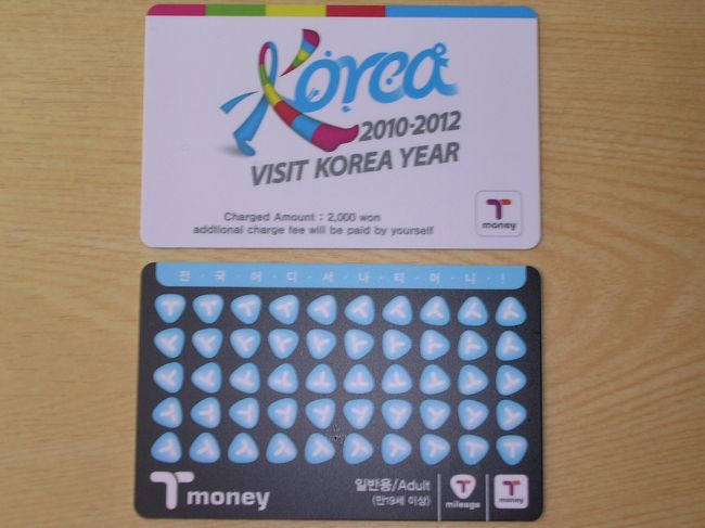 定刻とおりにソウル金浦空港に到着。空港からはタクシーではなく地下鉄を利用しました。今回のホテルまで新線の9号線で一本でいけたとのと、市民の様子がわかるし、車内の広告なんかも面白いし私は地下鉄派です。ソウルは相変わらず渋滞がすごいので地下鉄のほうが時間が正確だし。<br />ところで、ソウルに行きなれた方なら地下鉄やバスも利用する機会があると思いますが、そこで便利なのがごらんのT-MONEYカード。使い方は日本のSuicaとまったく一緒。改札でピッとタッチするだけでいちいち切符を買わなくてもすみ、しかも現金で買うより100ウオン安く乗れます。駅やコンビニでカード2500ウオン（日本円で200円位）で買い、希望の金額をチャージする仕組みです。ちなみにカードは買取式のようで、日本のように返却してもカード代は戻ってこないようです。<br />このT-MONEYに2000ウオン分をチャージしたものを、なんと金浦空港の到着口で配っています。写真上が配布カード、下が通常のカード。カードとともにデパートの割引券、化粧品サンプルなんかと一緒にパックにしてどうやら日本人の女性だけに配っているようです。カードには「VISIT KOREA YEAR」<br />と書かれていて裏には旅行者向けと書かれています。2000ウオンは、地下鉄の往復ができる程度ですが、カード代も考えたら4500ウオン分ですので、もらわない手はないですよ！