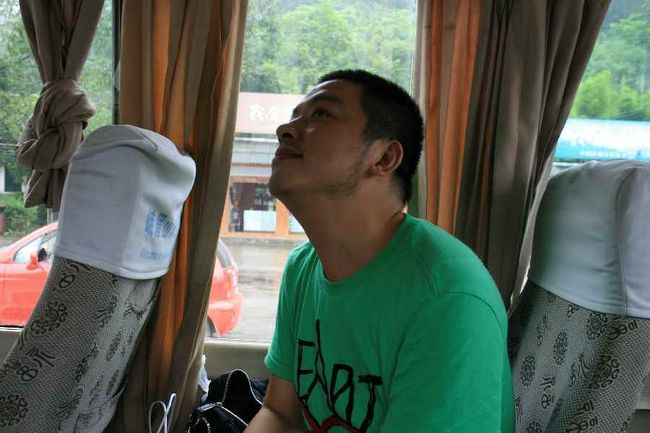 峨眉山の麓から金頂までは<br />専用車からバスに乗り換え、ロープウェー、金頂へと向かいます。<br /><br />写真はAra Chinaガイドの易さん。<br />楽しい雰囲気を作ろうと、話の糸口を探してくれます。<br />「好きな色は？」「好きな歌は？」<br /><br />どうも歌が得意のようです。<br />バス（片道２時間）の中で何曲か歌ってくれました。<br />日本の演歌ＯＫ！なかなかの美声。最終日に歌ってくれたチベットの歌は特に感銘を受けました。<br /><br />Ｔシャツに大きなハートマークのプリントがあったので<br />「新婚さん？」と聞いてみたらビンゴでした。<br /><br />