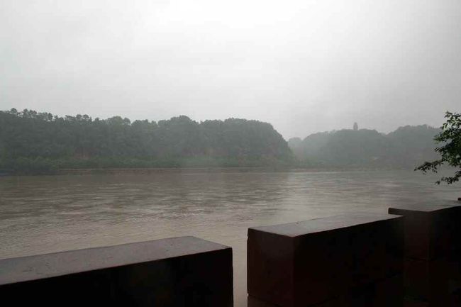 楽山眠仏。<br />対岸から、大仏が寝ている姿がかろうじて分かりました。<br />楽山大仏坐像は、大仏の足元付近でうごめいている観光客は分かりましたが、雨が激しくてそのお姿までは不明。<br /><br />雨天のため、楽山遊覧船は欠航。<br />「峨眉山とここはもう一度来よう！」と友達と約束。<br /><br />すぐ近くのレストランへ。<br />実は、地元のちょっとしたご馳走を兼ねてよりガイドさんにリクエストし、楽山の名物料理を用意してもらいました。<br /><br />楽山で有名なのは、豆腐と淡水魚の料理だそうです。淡水魚はピリ辛の味付け。そのほか、アヒルの肉、スープ、野菜の炒め物が並びました。<br /><br />易さんの味覚は日本人に近いらしく<br />それで日本人好みのお店を紹介することができるとか。<br />「ヘン　ハオ　チー」<br />楽山のお昼をあっさり味で堪能することができました。<br /><br /><br /><br />