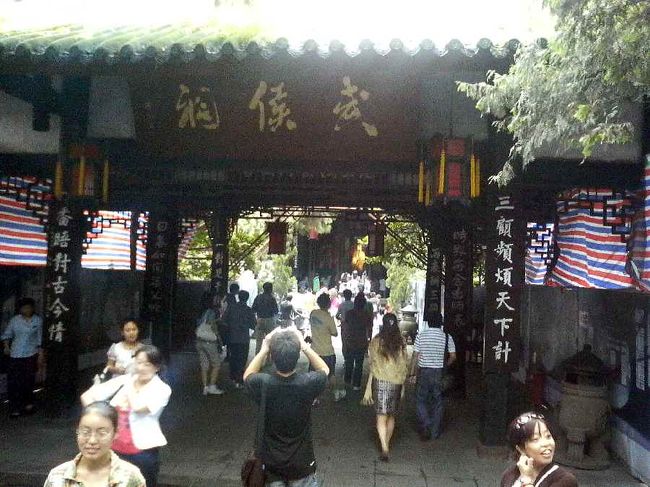 武候祠。<br />武候とは、孔明の贈り名で、忠武候をまつるところ。<br />上の漢昭烈廟を見たあと、今度は<br />この扁額を潜って諸葛亮を見学します。<br />明代に劉備と諸葛亮を一緒に祀るようになったとか。<br /><br />劉備と諸葛亮とは身分の違いにより、建物に高低をつけたり、それぞれの像を比較すると、服装や冠などに違いがあります。でも、やっぱり孔明のほうが人気あるみたい。<br /><br />ここでトラブル発生！<br />一眼レフのバッテリー切れ。<br />孔明像撮影できず…<br />これから携帯画像にチェンジ。