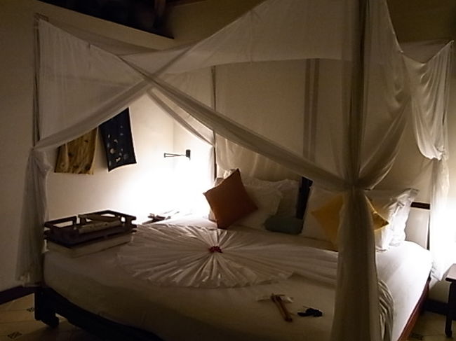 空港に来たのはアナマンダラの専用車、私達2人に対してスタッフが2人。乗る前にレモングラスのいい匂いの付いた冷えたおしぼりとお水を渡された。<br />そして満点の星空の下、海沿いの道を30分ほどすごいスピードでとばす。やけに乗り心地がいいと思ったらベンツ！<br /><br />フロントを通るとまずフレッシュジュースとジェラートのウエルカムを受けて、お部屋へ。<br /><br />これが夢に見た例のシーツのかざり！！