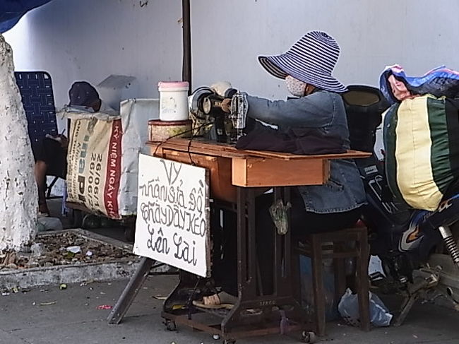 おばちゃんが外でお直し屋？を開いていた