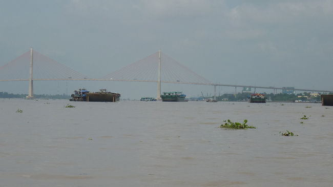 浮き草がプカプカと流れて来る川を、心地よい風を受けて進んで行くと、新たにベトナムにいる実感が沸いて来ます。<br />向こう側にはきれいな橋が架かっています。