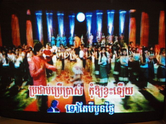 アプサラや小猿たちの踊りを堪能して、カンボジア鍋や揚げバナナも味わって、ホテルに帰ったのは22時過ぎ。私は海外でテレビを見る時は、なるべく現地の番組をつけるようにしています。<br /><br />現地ではどんな番組が人気なのか、どんな番組があるのかが知りたいから。<br />カンボジアでよくつけていたのは、これ。カラオケ番組。ちゃんと歌詞も出るんです。映像部分は多分、有名な俳優さんが出ているものだと思います。夜なんかずーっと放送していましたが、一日中やっているのか…ちなみにNHKもちゃんと受信していました。なんか、海外で見るNHKって不思議な感じ…。<br />