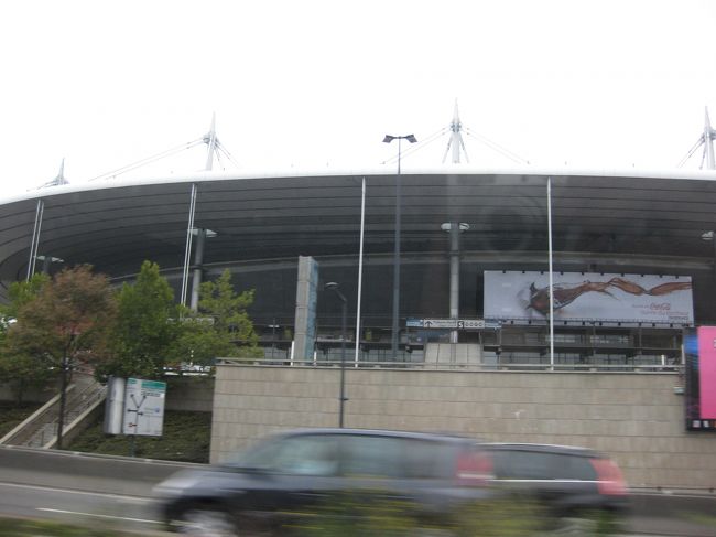 シャルルドゴール空港に、定刻どおり到着。<br /><br />送迎サービス付きだったので、出口でドライバーを<br />探しました。<br />日本人女性のガイドの方がにこやかに出迎えてくださり<br />現地ドライバーもとても感じのよい方でした。<br />日本語もとてもお上手。安心して、ホテルに向かいました。<br /><br />車内で、２日後にストでベルサイユ宮殿閉鎖の噂がありますよと<br />教えてくださいました。<br />こうなることもある程度、予想していたので、仕方ないなあ<br />と諦めました。<br /><br />写真は、パリへ向かう途中。<br />ワールドカップ開催時のメインスタジアムだったそう。<br /><br />どんより曇り、とても寒いです・・・