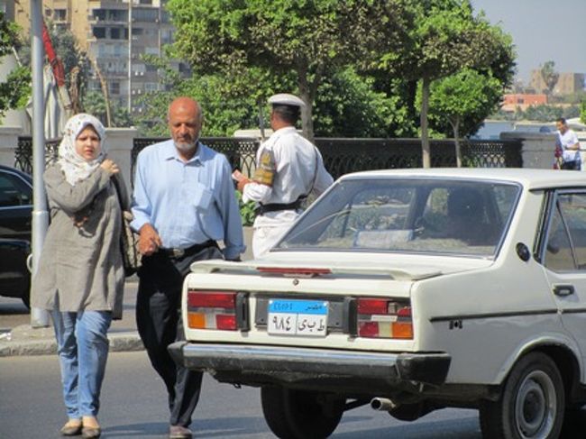 デパート散策を終えてホテルに戻りました。<br />お買物する予定でしたが、あんまり開いてるお店がないので、<br />ウインドーショッピングでした。<br />後で聞いたら、全部開店するのはお昼くらいらしいです。びっくり。<br /><br />帰り道に道を渡る男女。親子かな？<br />男性の服装は日本とあまり変わりません。<br />安い物売りや田舎のおじさんはガラベーヤを着ていますが、一般の人はこんな感じです。<br />若い女性は数からいうと、こんな折衷タイプの人が多いです。<br />