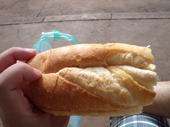 朝ご飯に、バスターミナルの脇で売っていたフランスパンのサンドイッチを買いました。写真は半分にカットされたもので、2つ（1本）で5,000k。買う時にソースをかけるかどうか聞かれたので、何か分からないけどかけてもらった。<br /><br />味はピリ辛でおいしかったです。