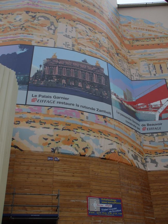 「ガルニエ裏の保護看板」<br />間違いない。<La Palais Garnier>とかいてある。パイプの足場をくぐって館内に入る。１０人位の行列があったので並ぶ。列の先頭にいる職員になにか聞いて帰って行く人が何人かいる。変だなー。私たちの番になった。「フリーけんがくチケット、シルブプレ！」これでは通じない。手振りで館内をぐるーっとまわす。職員はわかったか分からなかったか「ノン！xyz…！」お愛想もない。ダメのようである。修理中なのでダメなのかなーと思った、が残って行列している人もいる。分けがわからん。未練がましくウロウロしているとどんどん行列に並ぶ人が増えていく。帰って行く人も多い。オペラ座のカキコミには見学不可のブログがいろいろあった…？…そうだ！１０月1日、今日はオペラ座２０１０年シーズンの幕開け公演日ではないか。公演日は館内見学はできないはず。並んでいる人たちは当日券や前売券のために並んでいるのだろう。公演日それもシーズン幕開け日にぶつかったのではショウガナイ！今日来た事をメモリアルデーとして「シャガールの夢」をあきらめた。