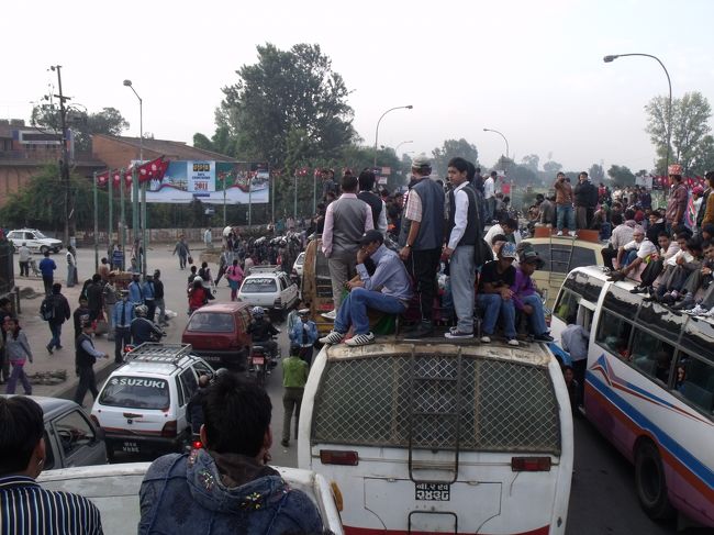 ネパールの２階建てバス。乗客は外に足を出して座る。自分は危ないので、中心部の荷物の上に乗る。７時ごろに出発するが、全部のバスが一緒に出発するのではないかと思うほどだ。通りに出て、１００Mも走らないうちに、バスが２０台以上止まって、皆気勢を上げている。<br />スターティングフェステバルかと聞くと、そうだと言うが、どうもおかしい。警官は武装している。<br /><br />その内、屋根の上の人間は降りて、向こう側に行けと言われた。ジャーマンもおりていく。自分は荷物から離れるのは嫌なので、車内に無理やりもぐりこむ。<br />どうもVIPが通るので、屋根の上に人が乗っているのは恥ずかしいと思っておろしたのではないか。１時間くらいのロスタイム。