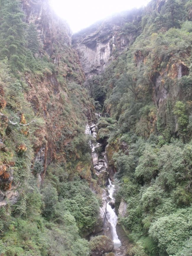 滝のすぐ左上から、飛行機が現れ飛び去っていく。爆音が聞こえカメラを構えるが、滝と同時に写すことは自分にはできなかった。１時間に５機ぐらいは飛んできたり、行ったりするので、じっくり構えれば簡単だとは思う。HPで滝にぶつかるように着陸とあるのは、こんなことなんだ。<br /><br />１２：３０広見　天来石見たいのがあった。大きな石に溝を刻み、１Mぐらいの高さに水を通し手あったので、シャワーをする。なんと気持ちの良いことだろう。上半身裸になり、体全身をふく。<br />天然の岩屋などがあり、昔からの宿場であろう。飛行場ができるまではルクラなんて重要な町ではなかったはずだ。<br /><br />トレッキングとはオランダ語の「Trek（旅をする人）」から来ており、<br />１９６０年代外貨が欲しいネパール政府が、観光客誘致の為にヒマラヤの山歩きをトレッキングとして売り出した事から始まる。<br />昼飯　あまりに子供がかわいくナマステと両手を合わすので、おもわず氷砂糖を上げた。お母さんに見せに行った。