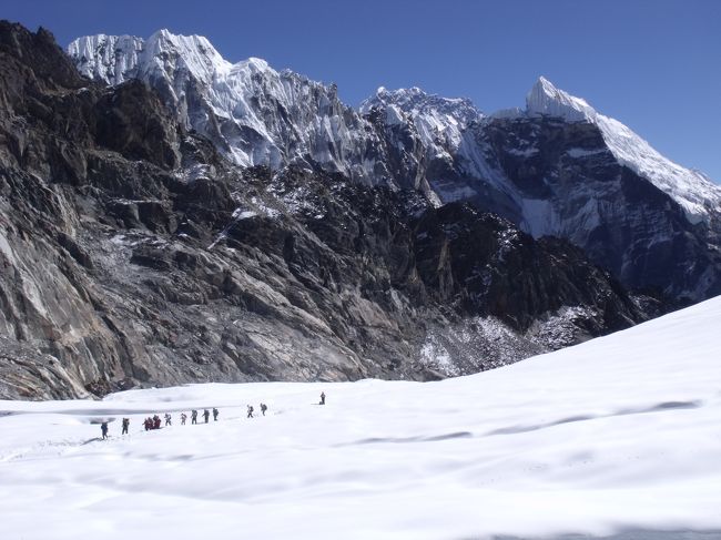 峠の向こう側には、クレパスが大きく口を開け湖になっている。<br />その向こうは雪原で、クレパスがあるのかしわだらけ。<br />懸垂氷河も山にくっついている。峠は暖かかった。お日様はありがたい。<br /><br />一服していると、「ついた」との声に「ごくろうさん」と声をかけたのになんとなくつれない。<br />11人グループ登山の連中だ。カラパタール側から登ってきた。他人には冷たい営業登山隊だ。<br /><br />モンスーンの影響で、ヒマラヤの氷河上に雪が降り積もるのは夏。溶けるのも同じく夏で、<br />冬に雪が降り、夏に溶けるほかの地域の氷河とは異なる。この特徴が、ヒマラヤ氷河が世界的にみても縮小速度が速いという結果につながっている。