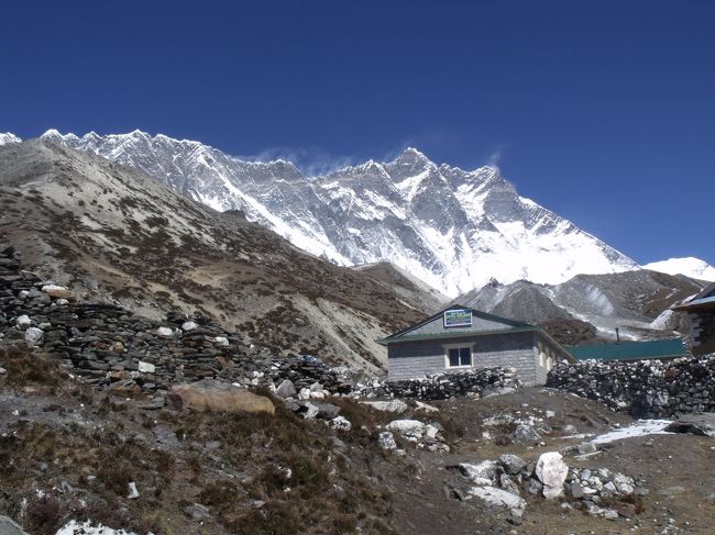 クリシュナは煙草を買いにどこかへ行ってしまった。日向ぼっこは気持ちが良い。<br />タイツを脱ぐ。ヘリコプターがこちらに向かって、超低空飛行で降りてくる。<br />Uターンして村に降りてきた。着陸地点が山裾で直接降りられないようだ。<br /><br />山襞の上に頭を出しているのはローツェ登る者と、下る者の差が激しい。チュクンリも相当きついようだ。どんどん進むと、前に見えていたヒマラヤヒダが、いつのまにか右になる。<br /><br />１１：２０Lunch Plase　直角方向にヌプチェと白い山。イエローバンドが良く見える。ネパール人が担がれてきた。ポーターのようだ。ポーターでも高山病になるときはなるらしい。ラーメンを頼む。何所でも中国製のインスタントだ。自分は少し硬いのを食べ始め、ちょうど良いころには食べ終わるのだが、このラーメンは食べ始めは固くてまずく、すぐに柔らかくなり過ぎまずくなる。卵を入れてもらえばよいがなかった。<br />いくらと日本語で聞いて２００RP渡すとOK,OKと済まされてしまった。<br /><br />