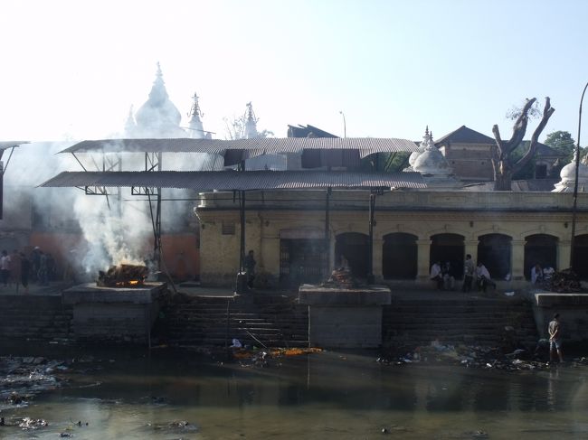 リングロードを進むと、パシュナートテンプルに出た。火葬場だ。ここも３５年前に来ている。<br /><br />バスが止まっている駐車場から土産品売場がずらーと並んでいる。<br />あまり買いたくなるものはない。アンモナイトなんか灰皿にでも使えるように、<br />少しは加工するとかすれば２０ドルぐらいに売れるだろうに、２ドルくらいで売っている。<br />ネパール人は商売が下手である。<br /><br />対岸にバイクを置いて、いつでも見ていられるようにする。<br />もうすでに２つは燃え上がっている。火葬場の方へ行ってみる。<br />小さな門をくぐり河岸に入る。ここはヒンズー教の人しか入れないことを後から知る。<br />ヒンズー教徒は、墓を作らないし、死に対してあっけらかんとしていると聞いていたが、<br />やはり親族との別れは同じで、ワァンワァン泣いている。<br /><br />しかし、それにしても汚い川だ。少しは環境整備とかして、聖なる河らしくしたらどうでしょうか。
