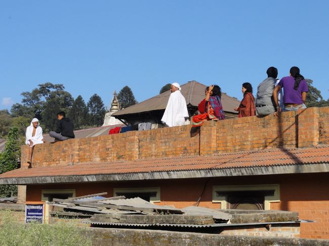 寺院へ向かう道のそばの建物に若い人たちがじっと座っている。<br />白い服は最近親をなくした人で、13日間こうして喪に服している。