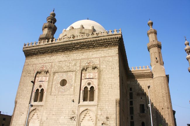 左側のガーマ・スルタン・ハサンです。<br /><br />マムルーク朝時代（1250-1517年）の1356年から1363年にかけてスルタン・ハサンが建てたもので、マムルーク建築の傑作といわれているそうです。<br />建物の石材はギザのピラミッドのものを使っているとも。<br /><br />なお、このモスクには先ほどのガーマ・アフマド・イブン・トゥールーンよりも高い９０ｍのミナレットがそびえていますが、安全上の問題から現在は昇ることを禁止されています。<br /><br />こちらからのパノラマも楽しみだったのに、残念。