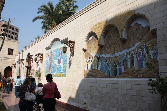 中庭の壁にはモザイク画が描かれており、アラビア語とともにコプト語も刻まれています。<br /><br />コプト語は現代エジプト語とも呼ばれ、古代エジプト民族の言葉に最も近いと言われているそうです。<br />表記については、イスラム化以前にエジプトを支配していた東ローマ帝国（ビザンツ帝国）時代の公用語であるギリシャ語の影響を受けたアルファベットになっています。<br /><br />現在では、コプト語は教会などのわずかな儀礼で用いられているほかは、日常生活で用いている家庭はほとんどなくなっているそうです。