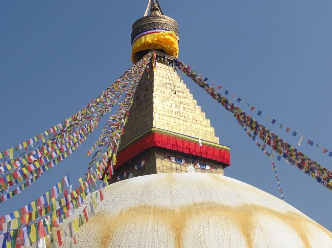 ガイドブックどおりのでっかいストゥーパ。<br />寄進されたタルチョがはためいてとってもきれい。<br />「タルチョどうですか？」みたいなことをいわれたけど、今回はごめんなさいということで。<br />塔のてっぺんにだれか登って新しいタルチョをつけている。<br />当然古いのははずされて、無造作に下へ投げ落とされる。<br />４面の仏陀の顔の上のほうに一箇所はしごがあってここから登っていくのが見える。<br /><br />