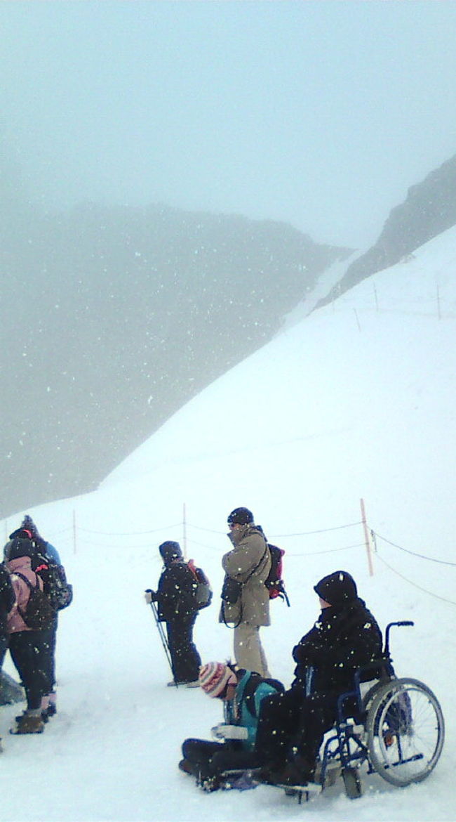 だ〜ん！！着きました。…ってこれ<br />一面のパノラマは？？　緑の山々とかは〜？？<br />ええ、山の上では「雪」がふっておりました。しかもかなり。<br />８月なんですけど…。夏のスイスの絶景がぁぁ…。<br />でも、まあ、８月でこんだけ降る雪を見るっていうのも旅の思い出かな？<br />まさにホワイトアウトな世界で、何を撮っても「真っ白」でした。<br />でも写真の車椅子の方でもこれちゃう４０００ｍ<br />日本じゃナイですよね〜〜〜<br />
