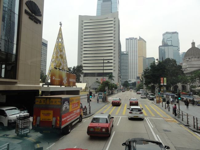 やっと渋滞から抜け出て、大通りに出ました<br /><br />あっ！昨夜見たスワロフスキーのツリーじゃないかな？<br /><br />昼見るとちょっとイメージわかないけど、左はやっぱり昨日見たイギリス風の立法局大楼だもんね<br />間違いないこれが皇后像広場だ〜<br /><br />