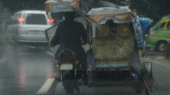 プルクラの車で１時間半程かけ山越えして行きます。<br />こんな土砂降りですが、通り抜ける街では地元の皆さん活発です。