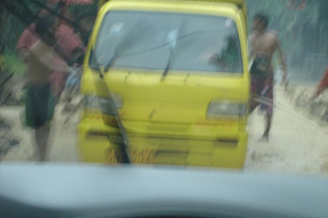 ぬかるみにはまって動けなくなったワゴン車に地元の人たちが寄ってきて押し出すところ。<br />すごく慣れた感じでした。