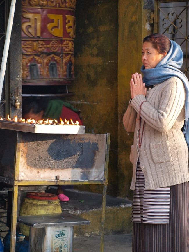 マニ車の前で祈る女性