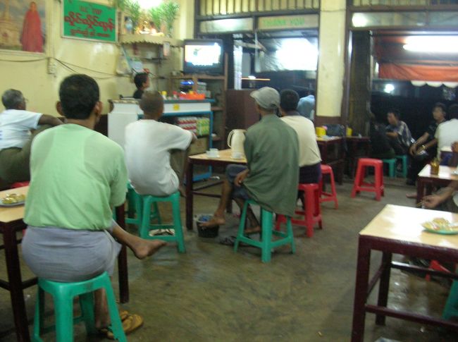 カフェではみなTVに夢中なのですが、実はTVの横ではラジカセでミャンマーのポップスらしきものを大音量でかけているので TVの音はまったく聞こえず、みな字幕だけで文句も言わず見ております。ちなみにTVではジャッキー・チェンのアクション映画を やってました。 