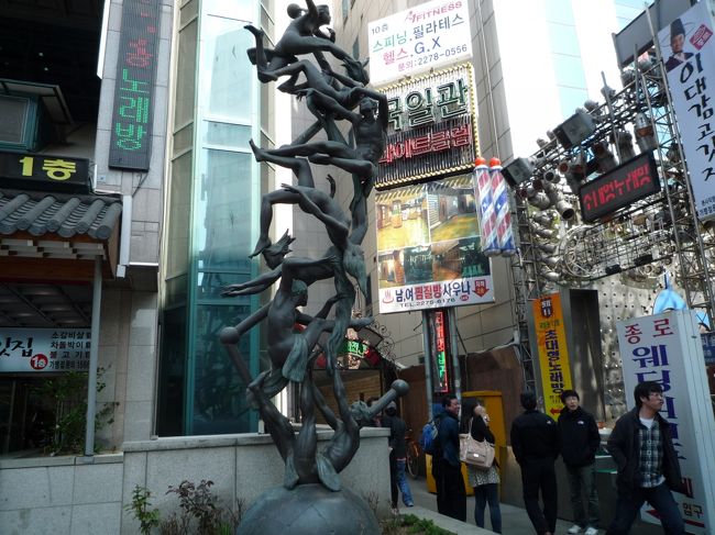 ほろ酔いでチムジルパンへ〜。<br />いつも行く鐘路の『ドリームパレスサウナ』です。<br />この絡まる人間オブジェが目印の建物の地下2階。<br />昼間の入湯料W6000＋チムジルパン室内着W1000　計W7000（525円）<br />夜間の入湯料はW9000。<br />結構泊まっている人多いらしくて入口にキャリーケースがいっぱい。<br />ここは清潔で広々してる割には比較的すいてて使い勝手がいい。<br />垢すりはW17000（1280円）。サッパリした〜♪