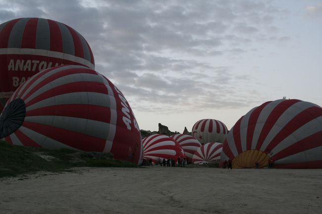 朝５時にホテルの入り口へお迎えのバンが登場。<br />トルコ時間だからきっと遅いだろうと思っていたら意外に正確。<br />ホテルと同じUchisar村にあるアトマスフィアバルーンのオフィスへ集合しました。<br />HISと提携しているのか、結構いろんなところでそのロゴが。<br /><br />入り口で受け付けをすると、<br />パイロットの名前の付いた安全のしおりを渡され<br />チャイやエキメッキをいただきつつ寛ぐ。<br />お手洗いはホテルかここで済ませないと<br />このあと２時間くらいいけません。<br /><br />30分くらいでパイロットの名前ごとにバンに分乗し、出発。<br />Goremeの北側の野原まで移動し、自分の乗る気球が膨らむまで<br />他の気球がどんどん上がっていくのを見、テンション一気に上昇！