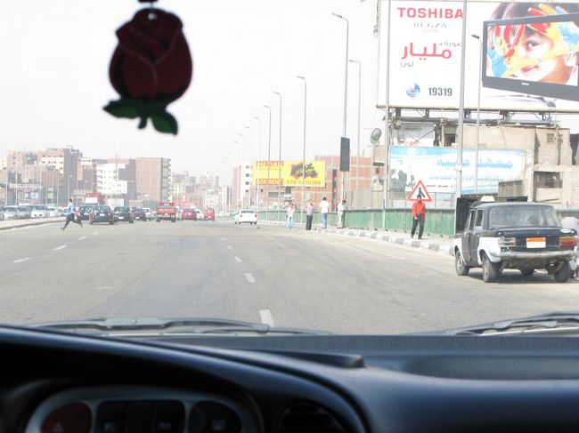 AM8にイミグレ手前の旅行カウンターへ行き、パスポートを旅行会社へ預けたまま特別カウンターを通ってエジプト入国。<br />パスポートのない状態にびくびくしつつ車へ乗り込むと私一人で出発。<br />あっ、個人ツアーなんや。ラッキーと思い運転手へ話しかけるも<br />まったく英語がわからないとのこと。<br />しかもみんな交通ルール無視するし、高速を普通に人渡ってるし、、、、<br />この国やばい。<br /><br />そう思っていたら写真のあたりで急停車。<br />正直さらわれる事を覚悟しました。<br />オイラさらってもたいした身代金もらえないよ〜と心の中で叫びつつ。。。<br /><br />とおもったらエジプト人英語ガイドが乗ってきました。<br />フランクな感じで一安心。