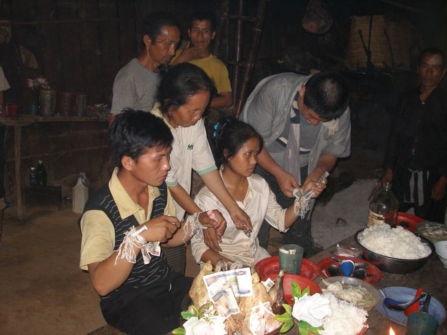 カップルの二人に参加者一人ずつが順番に２人の手それぞれにひもを結んで行く。飛び入り参加ながらひもを結ばせていただく。