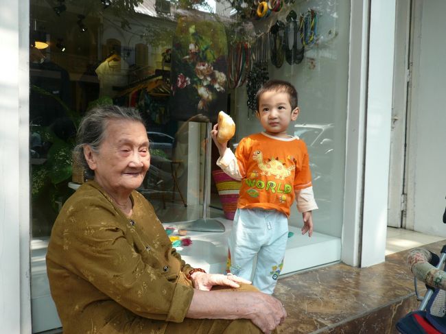 おばあちゃんと孫<br /><br />道が歩きにくいのは停めてあるバイクや車のせいだけじゃなく、建物の中は暑いから外で涼んでいる人も多いから。<br />可愛いおばあちゃんが孫の面倒を見ています。<br />ちなみに、こちらの人は写真をとられるのをあまり嫌わないんですって。