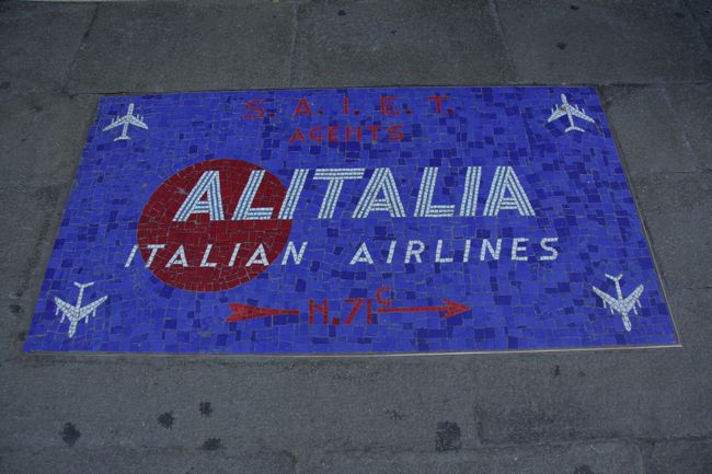 イタリアの航空会社アリタリアALITARIAの代理店AGENTのマークが路面にありました。大きさは約50×80ｾﾝﾁ。