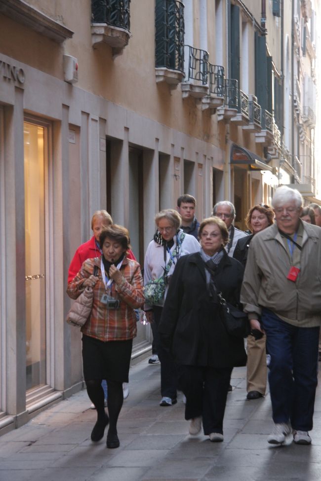 ヴァポレットを降りヴァッラレッソ通りから来るツアーガイド（左端）に引率された観光客。8：40<br />私は乗り場に向かっています。<br /><br />最近はイヤーホン・ガイドが普及してガイドの説明が分かりやすく、私のように写真を撮っていて少し遅れても、30ｍ程度は大丈夫です。<br /><br />この写真の説明を読んだ人が「イヤーホン・ガイド」は間違いで「オーディ・ガイド」と書くべきであると某サイトに投稿していました。<br />オーディオ・ガイドとは「録音・記憶したものを聞く装置and/or解説・説明方法」であることを知らないようです。