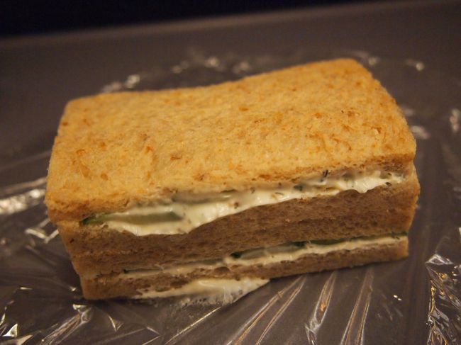 次から次へと映画を見ていたら、お夜食が配られました。<br /><br />手作り感溢れたサンドイッチ。サランラップに包まれてます。<br />中身はバターとキュウリ。<br /><br />なんだかちょっと楽しい。<br /><br /><br />コーヒーなど飲み物は、食事の時を除いて、セルフサービスでした。<br />機内の一番後ろに飲み物や飴・チョコを山盛り入れた篭が置いてあったので、軽く運動しがてら取りに行きました。