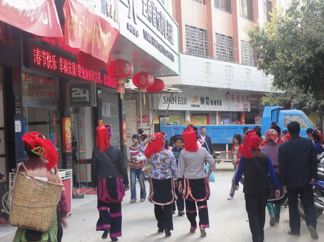 [緑春]<br /><br />　いったん景洪に戻った後、雲南の東側へと移動していきます。次の目的地は棚田で有名な元陽。景洪から元陽は道が悪いため、一日では行けません。よって、江城や緑春あたりで一泊することになります。何の期待もなく立ち寄った緑春ですが、これが大当たりでした。<br /><br />　緑春はハニ族の地方都市。街は山の稜線のような場所に位置し、稜線沿いに伸びる一本の長い道が町のメインストリートになっています。この町に来てまず驚くのが民族服を着た人の多さ。普通に小奇麗な町の通りを、綺麗に着飾った女性たちが行き来しています(写真)。