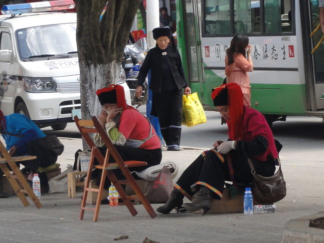 　単に民族衣装の着用率ならば、この後訪問する元陽近郊の方が上かもしれません。この緑春がユニークなのは、町が都会っぽいのに住民が民族服を着ていることです。そして、その着こなしも洗練されています。市場で野菜を売るオバサンも、通りを掃除する清掃員も、靴磨きの女性(写真)も、その職業が不釣合いなほどきれいに着こなしています。