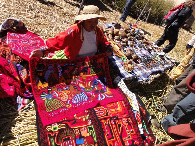 藁小屋の周りには、観光客目当てのお土産屋さんが並んでいます。<br />世界の例外に漏れず、値段は書いていません。<br />そう、値段を示したら負けと言わんばかりに。<br /><br />カラフルで可愛らしい布には、島の生活らしい絵がありました。<br />お母さんの手作りでしょうか。