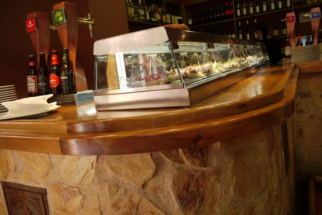 この店のメニューはピンチョスながら、メニューはタパスと書かれています。このLizarranでは、バルのエリアが、丁度、立ち食い寿司のカウンターのような店内で、ガラスケースに出てきたお好みのピンチョスをオーダーし、あとで食べた数だけ精算するという方式。ランチ時に並ぶピンチョスは少し軽めの具材が使われ、夕方に近づくとフライやお肉など多少、お腹にたまるものが中心に並びます。<br /><br />