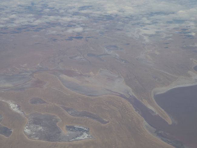 こんな景色が延々と続きます。<br /><br />そして、「間もなく着陸態勢に入りますので、全ての電子機器の電源をお切りください。」という英語アナウンスが流れたかと思うと、左前方に突如現れたのは大きな岩、そうエアーズロックでした。<br /><br />おおぉぉ〜、と大きな歓声が上がり、皆さん堂々とデジカメやビデオカメラで撮影。でも、全く動じないCAさん達を見ていると、いつもこんな状態なのかなと想像できます。ただ、私の隣の席が空いていたのですが、通路右の席に座っていた青年が私の隣へ移動してきたときはさすがにCAさんも「危ないから座ってください！！！！！」と叫んでいました。<br /><br />初めて見たエアーズ・ロックは、本当に感動的でした。