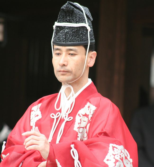 参加者の方々は皆独特の装束をしています。先ず、頭の被りものは烏帽子（えぼし）というものです。上衣は鞠水干（まりすいかん）で、生糸（練っていない）を用いて紗という織にしたものです。