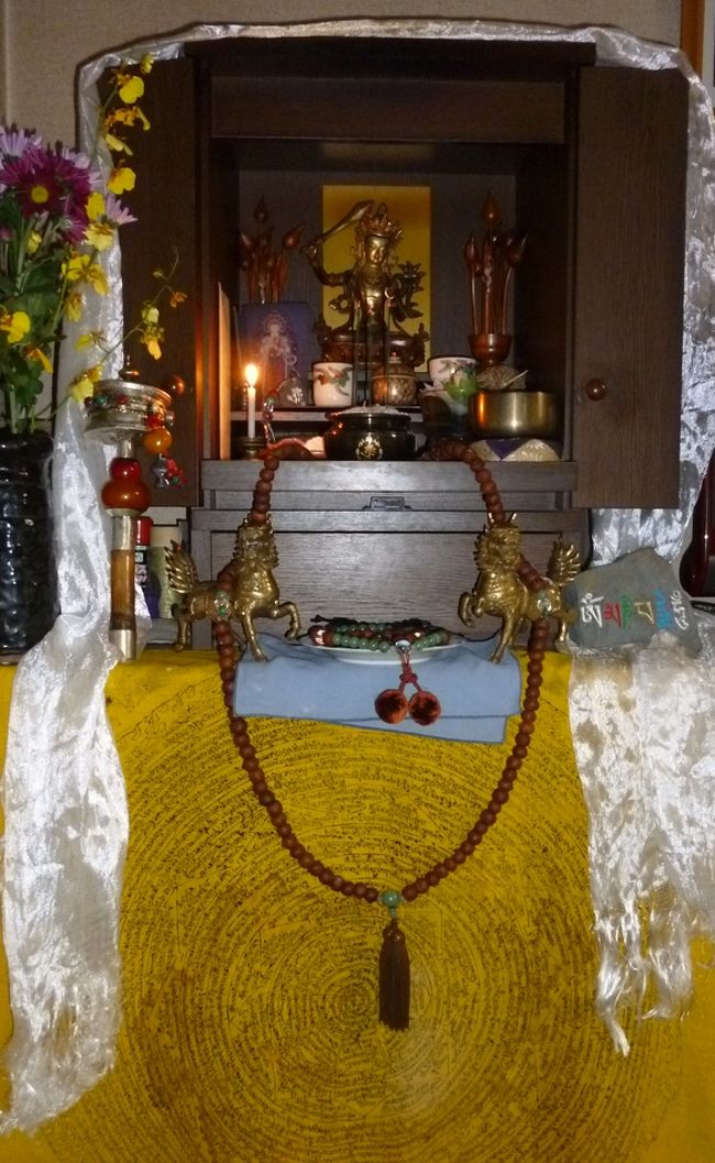 【エピローグEpilogue】　<br />　旅はいつかは終わる。そして、記憶としての新たな時間を刻み始める。<br /><br /><br />　鹿野山大接心から帰ってきた。これも一つの小さな旅であった。河野太通老師の提唱は、無門関第八則“奚中造車”。有にして無、『空』についてである。 <br /><br />　「チベットでの空（くう）とはそら（空）とその青さ」であった。 それは、輝ける光と深い青色の空間として、①それのみで存在し、朝焼け夕焼けなどにも変らぬ空として②本性を有し、宇宙があり、それを認識するものがある限り③永遠に存在する。<br />　空（くう）とは非実体だが、そら（空）は『実体』を成立させる三原則を満たしている。そんなことを小さな旅の帰り道で考えていた。<br /><br />　８月下旬、終戦記念日に関連して、とりためたVIDEOを見ながら、戦争そして人の殺し合いについて書こうとしていた。<br />　フクシマ原発から、非戦闘市民への当に直接投下という広島・長崎の原爆の非人道性、大東亜戦争における日本戦没者数は２３０万人。民間人死者数８０万人。<br />　第二次大戦全体での犠牲者数は5,335万人。戦死者数については、ソ連の1,450万人が図抜けて多い。<br />　“Heartｓ＆Minds”で描かれるベトナム戦争での無差別殺戮、“Pianist”のアウシュビッツ150万人の虐殺。映画“SevenYears　InTibet”　もあったが、中国はチベットで仏像を破壊したのみならず、何人の僧侶・人々を殺戮してきたか。その中国共産党も毛沢東の経済政策の失敗で3,000万人を死亡させたといわれる。<br />　その時のブログは、『人間というのは何者　－最も恐ろしい被創造物－』というタイトルにしたが、いまだに“下書き”のまま公開できない。<br /><br />　これらの事実は“悲しみ、哀しみ”というよりも“痛み”だろう。人間は、一方では東北ボランティアなどに見られるように、驚くばかりの優しさがあるのに、また、一方では戦争殺戮といった残虐な行為をしうるのか。そのダイナミックレンジの大きさに戸惑うと共に、精神の構造や心のあり方を仏教・宗教、唯識心理学に求めても、答えはなかなか見つからなかった。<br /><br /><br /><br />　チベット旅行のまとめ－エピローグEpilogueはチベットの悲しみについてである。それを旅の結論とするのは、まさに寂しいが、それはモーツアルトの曲の紺に近い“碧さ”　である。前回の続きのショトン祭後とツアー最終日のラサ郊外湖への遠足についても記してゆく。チベットブルーはそらの青さであったが、それは豊富な水の碧さでもあった。<br /><br /><br />（写真は現在の我が家の仏壇。チベットの思い出が詰まっている。文殊菩薩を仏として安置した。ロウソクの光に輝く姿は、まさにここしか無いというようにその場所にぴったりと収まった。手前一対の龍馬は仏を守護するかのように咆哮し鎮座している。仏壇の周りに掛けられた白い布はカタ（旅の安全を祈願して旅行者にマフラーのように掛けられるが、土産店が文殊菩薩を包んでくれ、チベットから来たもの）。左にはマニ車、右には自作マニ石、中央には数珠、手首輪を配し、セラ寺で求めた黄色布製の曼荼羅が背景となっている。線香立てにも虚空菩薩の梵字がある）<br />