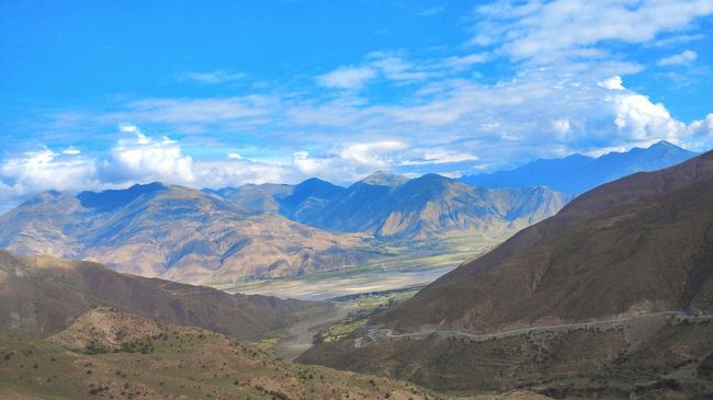 【チベットラサ遠景】<br /><br />　写真は標高の高い峠から遥かにチベットラサ市内の方向を望む。 <br /><br />　下記のチベット旅行記（ラサに到着！　チベット旅行記２：瑞樹さんの旅行ブログ）にチベットの歴史がきちっと書かれている。<br />http://4travel.jp/traveler/saemizuki/album/10169727/ <br />　自らの無知・無明を恥じるばかりだが、まずラサに侵入した外国軍は1904年のイギリスで、そのときもダライ・ラマ13世は一時モンゴルに亡命、1908 年には清軍侵攻でインドに亡命など、帰国したのちも知らなかったことが多かった。歴史的には、その後も武装蜂起や反乱、そして凄惨・悲惨な殺害・虐待が延々連綿として続けられる。それだけでなく、寺院や文化財も徹底的に破壊された。<br /><br />　『1989年にも大規模なデモが発生し、流血の事態に発展したそうです。延べ数十万人のチベット人が虐殺され、彼らの漢族及び”中国”に対する憎しみは今も消えていないようです。』　引用の旅行記は、青蔵鉄道が建設される直前の2006年04月29日〜05月07日だから、つい最近の北京五輪を前にした2008年3月の騒乱（暴動という言葉は使えない）は記載されていない。今回も民家を含めいたるところに中華人民共和国の国旗が掲げられている。『この暴動を好機と捉えた中国政府は徹底的なチベット独立派への取り締まりを行い、ラサ市内に多く居住していたチベット独立派は壊滅的打撃を受けた。』と下記ブログにある。 <br />http://ja.wikipedia.org/wiki/2008%E5%B9%B4%E3%81%AE%E3%83%81%E3%83%99%E3%83%83%E3%83%88%E9%A8%92%E4%B9%B1 