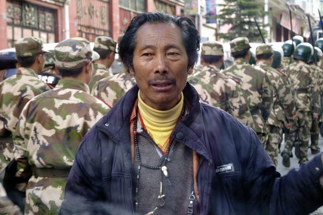 ひょうきんな運転手さん、日焼けで真っ黒です。<br /><br />後ろは人民解放軍の威嚇行進です。<br />もちろん自動小銃とか持ってます。