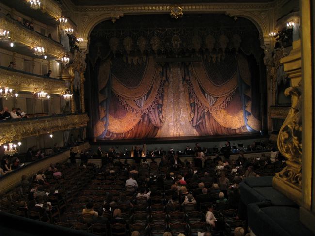 この旅の目的の一つだったマリインスキー劇場。入口を入ってすぐ右手の窓口で、ネットで購入済みのバウチャーを出すと、何事もなくチケットと交換してくれた。（恐らく）当日券を求めようとしている人々で結構な込み具合だった。着ていく物に迷ったけど、一階にはＴシャツの子供もいたりして、気にし過ぎる必要はないみたい。クロークが分からず、バックパックを持ったまま席についてたら、緑のジャケットの係のおばちゃんが怒鳴りながら預ける場所を教えてくれた。