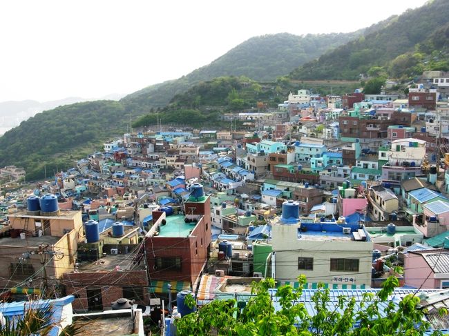 甘川洞を望みます。<br /><br />山の斜面にところ狭しと建てられた住宅。<br />甘川洞のみならず、<br />釜山ではこういった光景を随所で見かけられます。<br /><br />もちろん平野が少ないという理由が挙げられますが、<br />ここに住むことになった理由は別にあるそうです。<br />それは･･･<br /><br />朝鮮戦争で北朝鮮が侵略してきた時、<br />韓国内は戦地となり、国民は南へ避難せざるを得なくなりました。<br />釜山は半島南部のため、その避難民が押し寄せてきたそうです。<br />もともと住める土地が少なかったため、<br />避難民は山の斜面を利用して小屋を建て、<br />住み始めたとのことです。<br /><br />綺麗な風景にも悲惨な過去があったのですね。