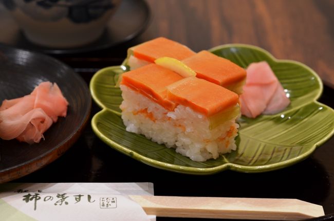 【柿の葉ずし】<br />柿の葉ずしは、古くから五条や吉野地方の家々で、ハレの日のごちそうとして親しまれてきました。<br />柿の若葉が瑞々しく育つ夏の頃から、柿の葉が赤く色づく晩秋の頃にかけて<br />夏祭りや秋祭りなど、特別な日を迎えるたびに、吉野川流域の家々では、柿の葉ずしがつくられました。<br />サバやサケの寿司を柿の葉で包み込み、すし箱に入れて押しをかけるという手法は古の時代から、この地方に代々伝わる伝統的なもの。<br />海のない大和の国では貴重な食材である魚を、保存性に優れた柿の葉で包むという先人の知恵が柿の葉の爽やかな香りがほんのり漂う格別な美味、今も変わらずに愛される、柿の葉ずしを生み出したのです。