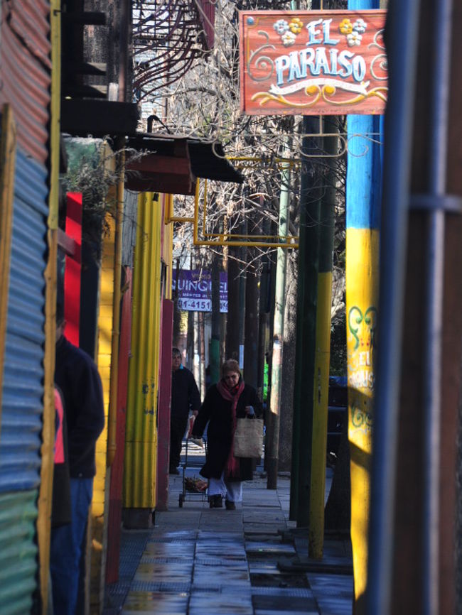 メイン通りから一本外れた通り。<br />買い物帰りの女性が足早に歩いてくる。